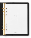 An open Filofax black leather-bound ring binder planner showing the Notairé January 2027 page spread with gold-tone metal rings and white pages.