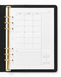 A black leather-bound ring binder Notairé  planner shown open to a white monthly  calendar overview and notes page, with gold-tone metal rings on a clean white background.