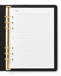 A black Filofax leather-bound ring binder notebook with gold-tone metal rings and a white Notairé lined notes page, shown from a top-down view on a white background.